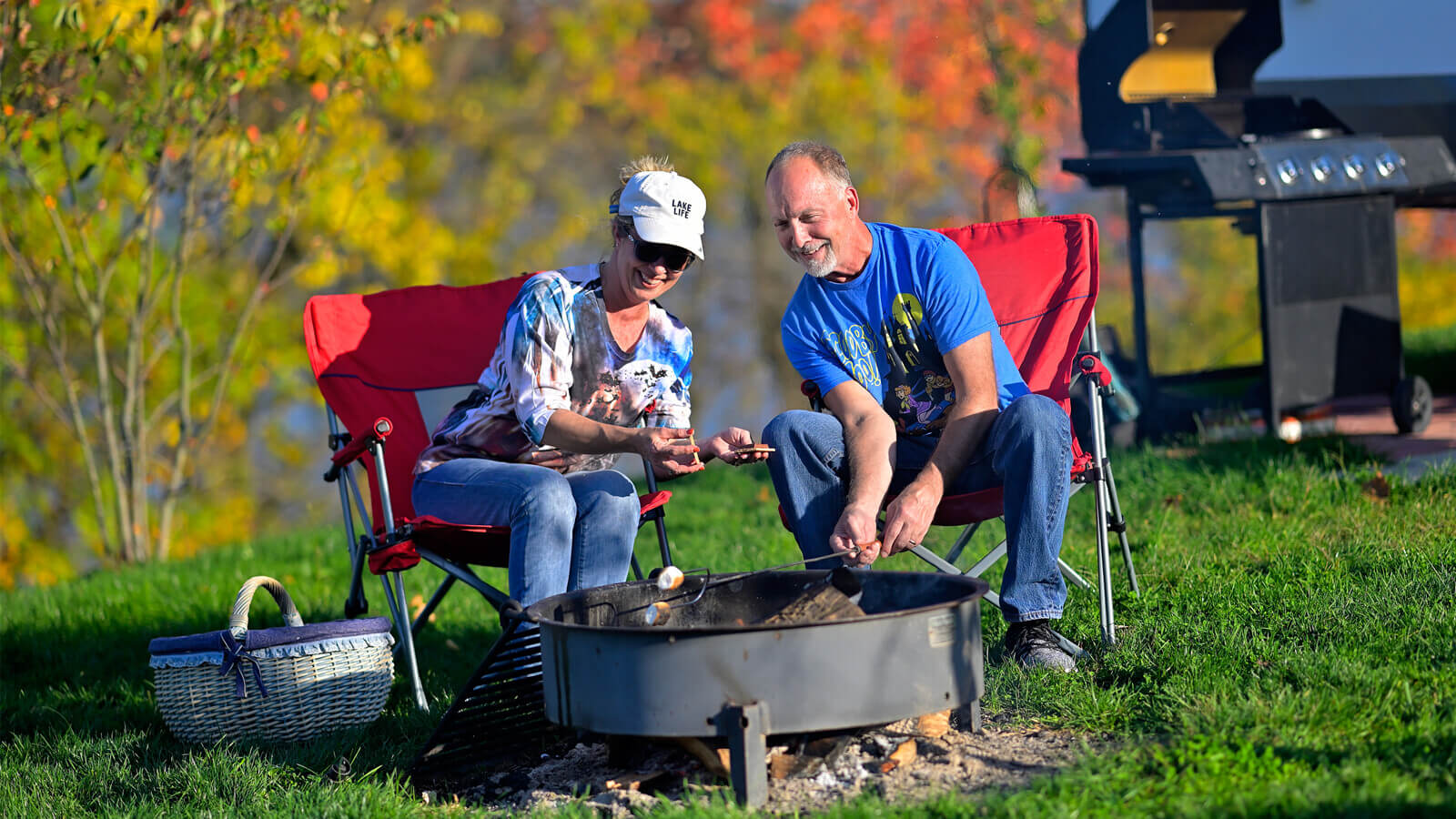Couple sitting around a campfire cooking smores