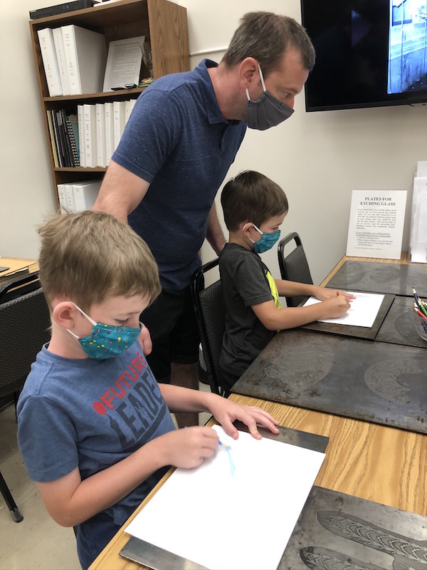 two boys and father doing etchings at the Cambridge Glass Museum